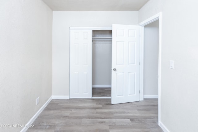 unfurnished bedroom featuring light wood-type flooring and a closet