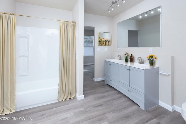 bathroom featuring shower / tub combo, wood-type flooring, vanity, and rail lighting