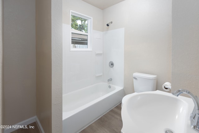 bathroom with bathing tub / shower combination, toilet, and hardwood / wood-style flooring