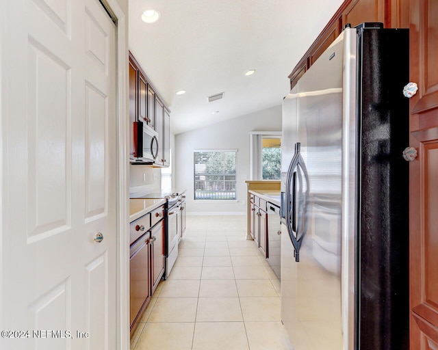 kitchen featuring light tile patterned floors, stainless steel appliances, and lofted ceiling