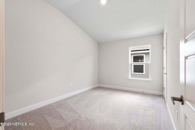 carpeted empty room with vaulted ceiling and a textured ceiling