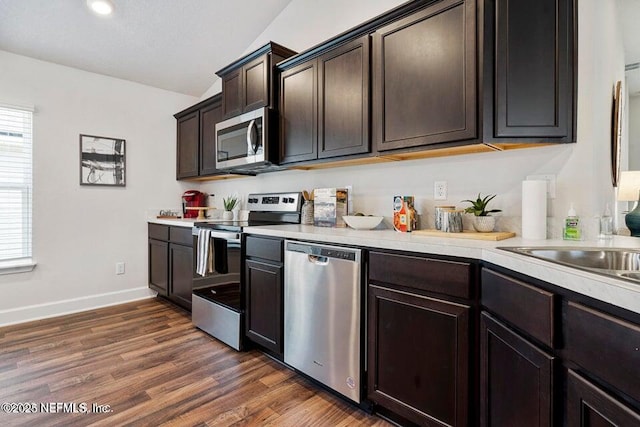 kitchen with appliances with stainless steel finishes, dark hardwood / wood-style flooring, and dark brown cabinets