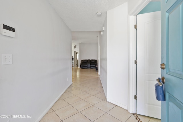 corridor with light tile patterned floors and a textured ceiling