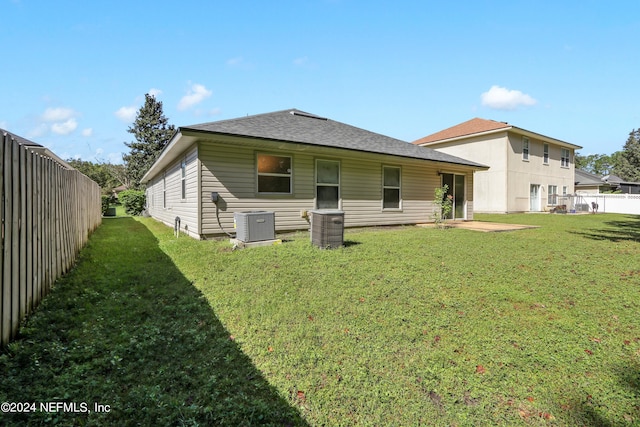 rear view of property with central AC and a lawn