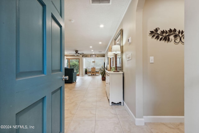 entryway with crown molding, ceiling fan, and light tile patterned floors