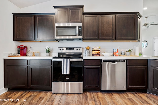 kitchen featuring dark brown cabinetry, stainless steel appliances, lofted ceiling, and light hardwood / wood-style flooring