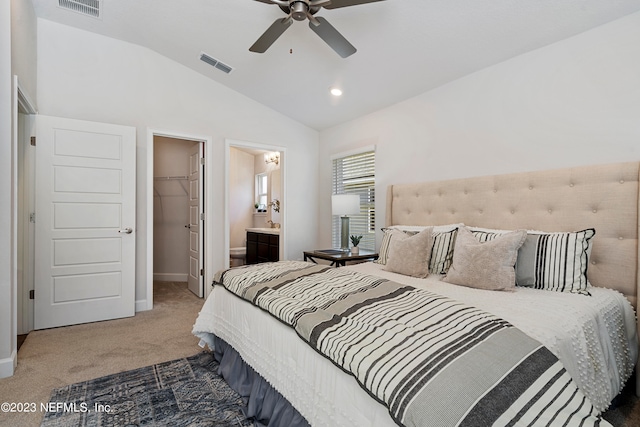 carpeted bedroom with a closet, vaulted ceiling, a walk in closet, ensuite bathroom, and ceiling fan