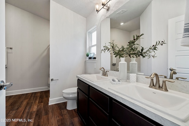 bathroom featuring a textured ceiling, hardwood / wood-style flooring, vanity, and toilet