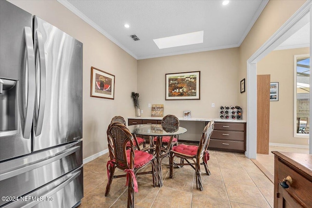 tiled dining room featuring a skylight and crown molding