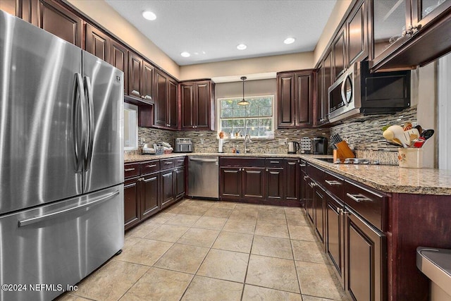 kitchen with decorative backsplash, pendant lighting, light stone counters, stainless steel appliances, and light tile patterned floors