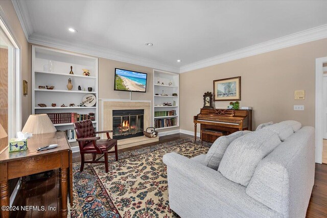 living room featuring ornamental molding, built in features, and dark hardwood / wood-style flooring