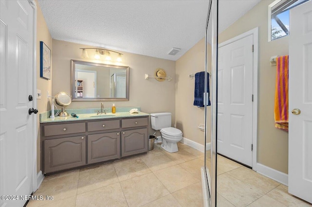 bathroom featuring toilet, tile patterned floors, a shower with door, vanity, and a textured ceiling