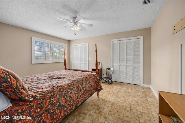 bedroom featuring ceiling fan, multiple closets, and a textured ceiling