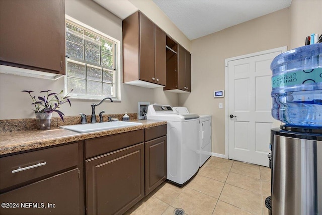 laundry room with cabinets, separate washer and dryer, sink, light tile patterned floors, and a textured ceiling