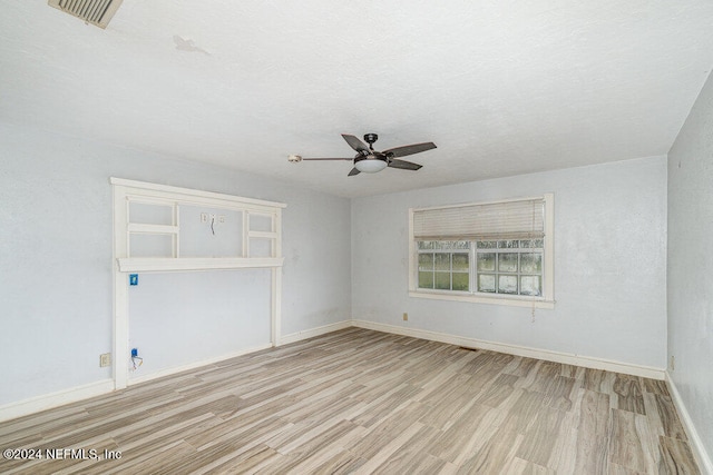 empty room with light hardwood / wood-style floors, a textured ceiling, and ceiling fan