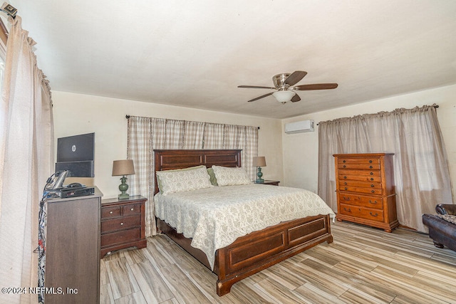 bedroom with ceiling fan, a wall mounted air conditioner, and light hardwood / wood-style flooring