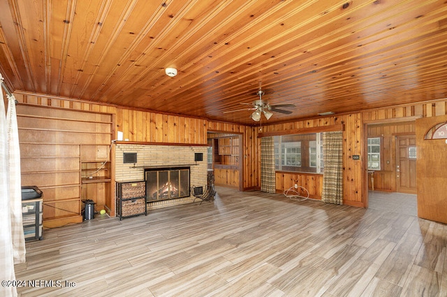 living room featuring wooden walls, light hardwood / wood-style flooring, a fireplace, and wood ceiling