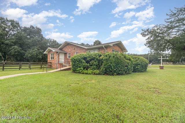 view of front of house with a rural view and a front lawn