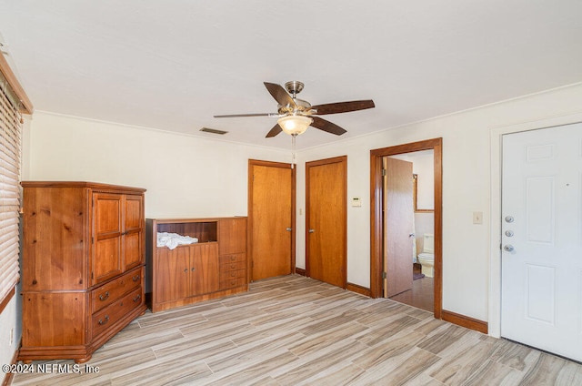 unfurnished bedroom featuring light wood-type flooring, ceiling fan, crown molding, ensuite bath, and multiple closets