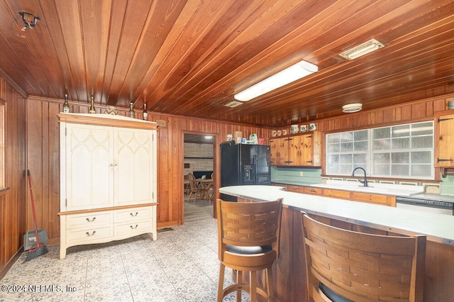 kitchen featuring black fridge, wooden walls, and wood ceiling