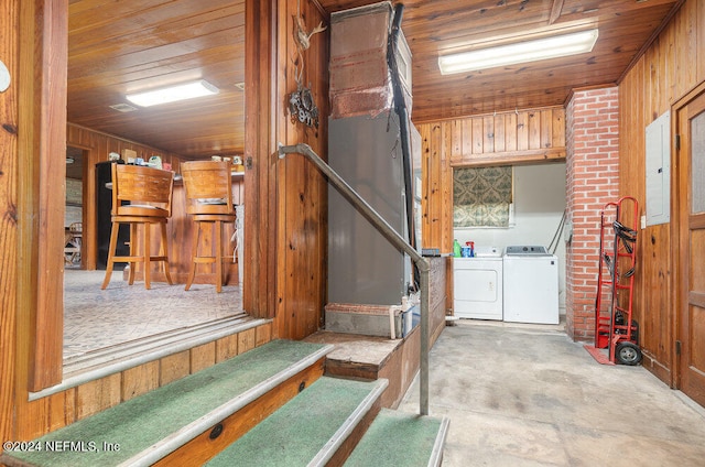 basement featuring wood walls, electric panel, washer and dryer, and wood ceiling