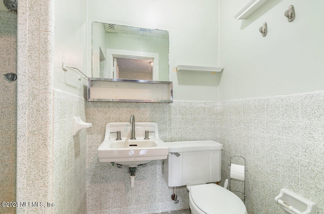 bathroom featuring tile walls, sink, and toilet