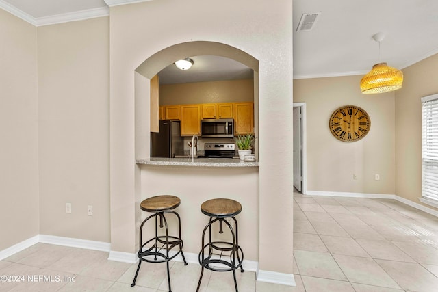 kitchen with pendant lighting, crown molding, a kitchen breakfast bar, and stainless steel appliances