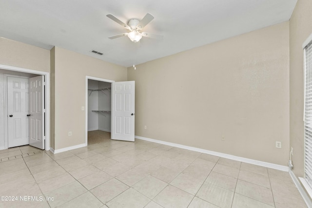 unfurnished bedroom with baseboards, visible vents, a spacious closet, and light tile patterned flooring