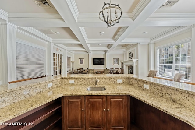 kitchen with coffered ceiling, visible vents, a sink, light stone countertops, and a notable chandelier
