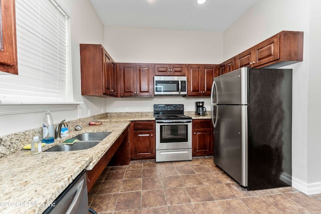 kitchen featuring light stone counters, sink, and stainless steel appliances