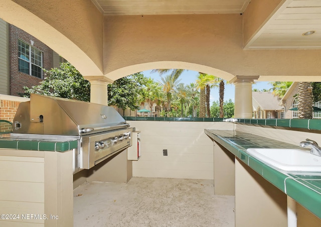 view of patio / terrace with a hot tub, an outdoor kitchen, sink, and grilling area