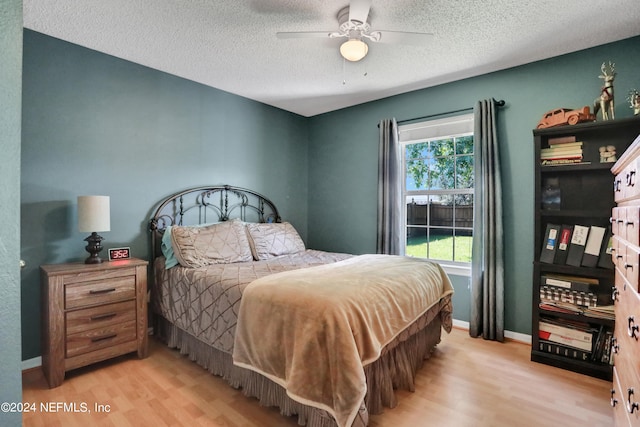 bedroom with light hardwood / wood-style flooring, ceiling fan, and a textured ceiling