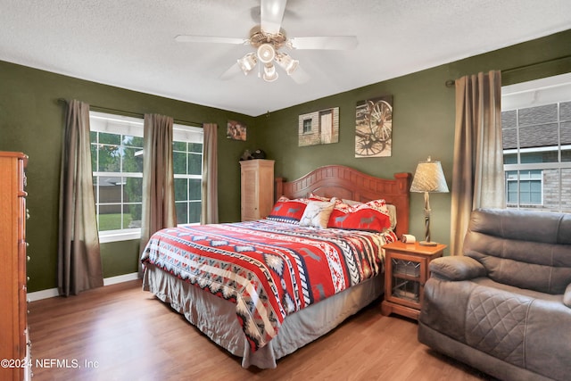 bedroom with ceiling fan, a textured ceiling, and hardwood / wood-style floors