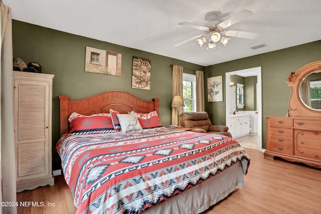 bedroom with a textured ceiling, ceiling fan, light hardwood / wood-style flooring, and ensuite bathroom