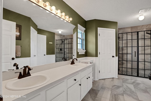 bathroom featuring vanity, a textured ceiling, and a shower with door