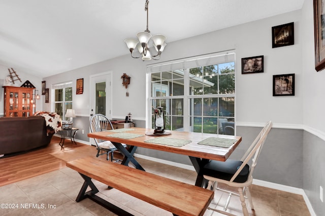 dining room with light wood-type flooring, vaulted ceiling, and a notable chandelier