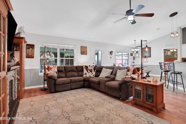 living room with ceiling fan with notable chandelier, lofted ceiling, and hardwood / wood-style flooring