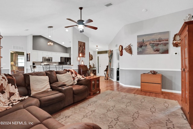 living room with ceiling fan, light hardwood / wood-style floors, and high vaulted ceiling