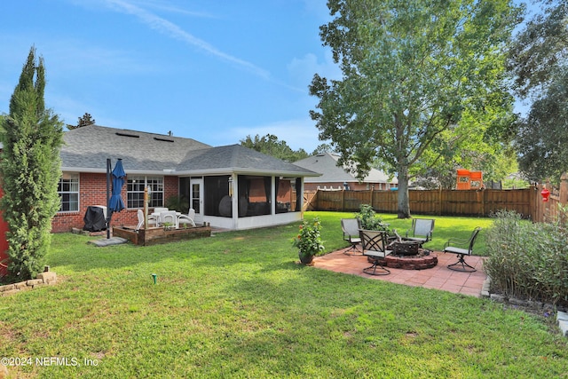 rear view of house with a lawn, a sunroom, an outdoor fire pit, and a patio