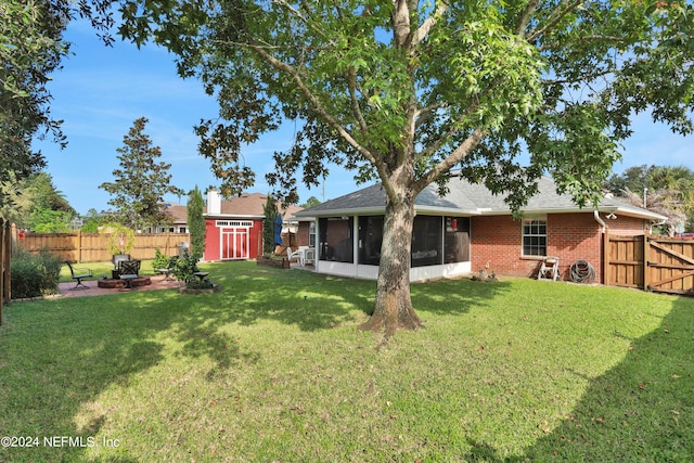 view of yard featuring a sunroom, a storage unit, and an outdoor fire pit