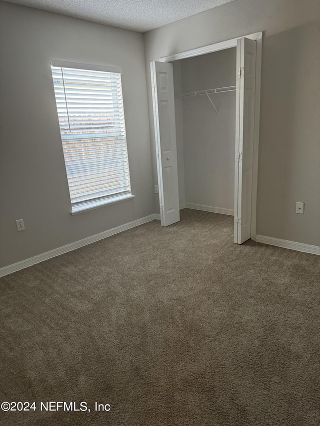 unfurnished bedroom featuring a closet, a textured ceiling, and carpet floors