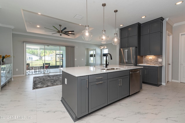 kitchen with a center island with sink, decorative backsplash, sink, pendant lighting, and appliances with stainless steel finishes