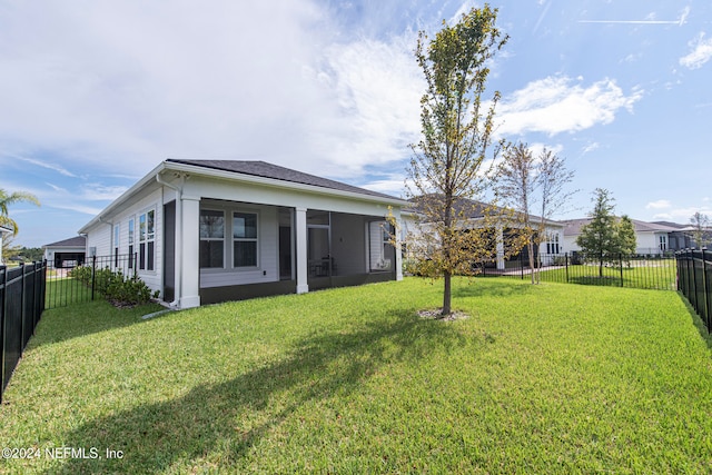 rear view of house featuring a lawn and a sunroom