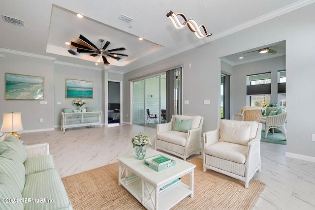 living room with ornamental molding, ceiling fan, and a raised ceiling