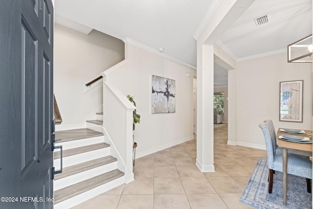 foyer with crown molding, light tile patterned floors, a textured ceiling, and an inviting chandelier