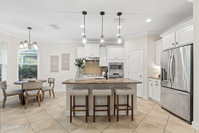 kitchen with white cabinets, stainless steel appliances, hanging light fixtures, and a center island with sink