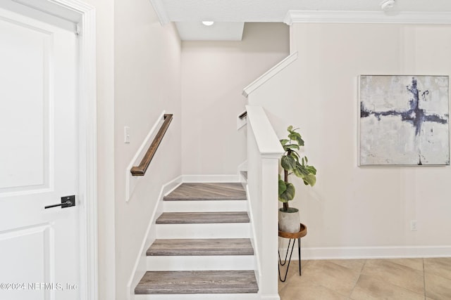 staircase with tile patterned floors, crown molding, and a textured ceiling