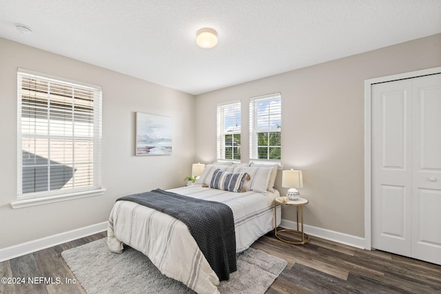 bedroom featuring a textured ceiling, dark wood-type flooring, and a closet