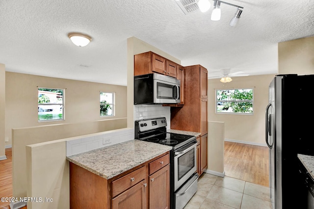 kitchen featuring stainless steel appliances, backsplash, light wood-type flooring, and a healthy amount of sunlight