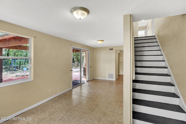 staircase featuring a textured ceiling and tile patterned flooring